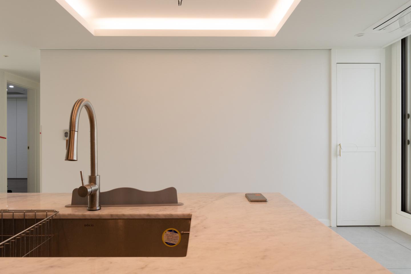 웜 브라운 컬러의 블라인드와 유리 도어 사이로 들어오는 햇살이 아늑하고 고급스러운 다이닝 공간을 완성하는 인테리어티쳐의 리센츠 아파트 주방 인테리어 바로 보러가기